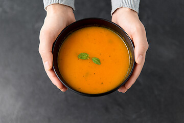 Image showing hands with bowl of pumpkin cream soup on table