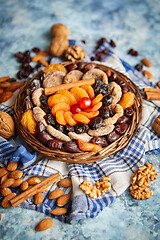 Image showing Composition of dried fruits and nuts in small wicker bowl placed on stone table