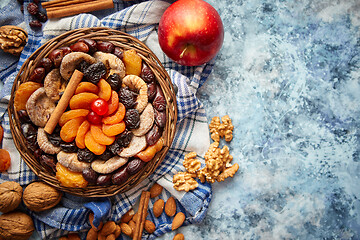 Image showing Composition of dried fruits and nuts in small wicker bowl placed on stone table