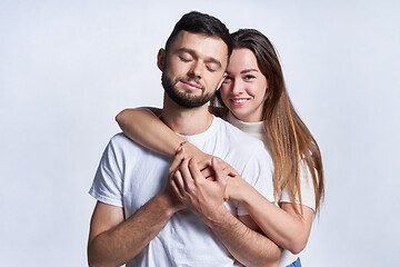 Image showing Smiling young couple hugging, studio portrait over light background