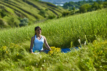 Image showing Young female sitting in green grass meadow in summer day