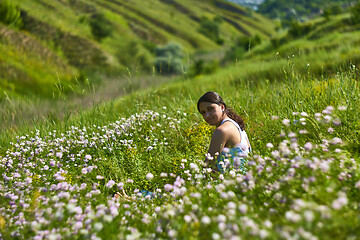 Image showing Young female sitting in green grass meadow in summer day