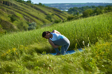 Image showing Young woman doing yoga in green summer meadow