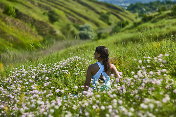 Image showing Young female sitting in green grass meadow in summer day