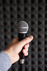 Image showing Woman hand holding vocal mic on acoustic foam panel background