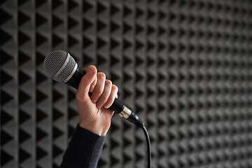 Image showing Woman hand holding vocal mic on acoustic foam panel background