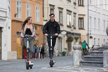 Image showing Trendy fashinable teenagers riding public rental electric scooters in urban city environment. New eco-friendly modern public city transport in Ljubljana, Slovenia