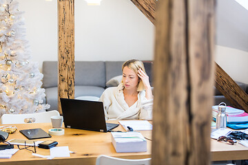 Image showing Young female entrepreneur wearing cosy warm bathrobe working remotly from home in winter Christmas time during 2020 corona virus pandemic. Work from home, selter in place, concept.