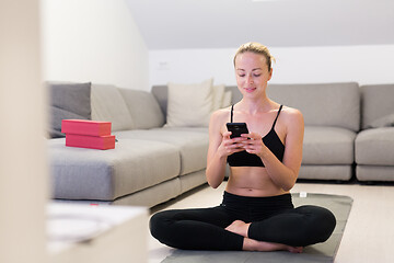 Image showing Beautiful blonde woman doing home workout indoors. Woman practice yoga at home. Fit girl using workout tutorials for healthy active lifestyle. Woman using quarantine for home workouts.