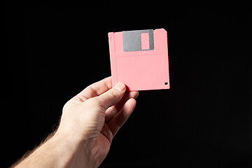 Image showing Human hand holding pink floppy disk