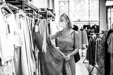 Image showing Fashionable woman wearing protective face mask shopping clothes in reopen retail shopping store. New normal lifestyle during corona virus pandemic