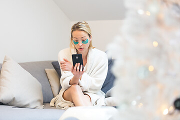 Image showing Woman at home relaxing on sofa couch using social media on phone for video chatting with her loved ones during corona virus pandemic. Stay at home, social distancing lifestyle.