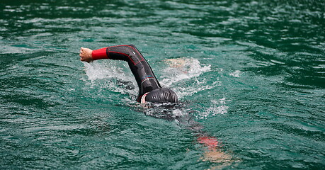 Image showing triathlon athlete swimming on lake wearing wetsuit