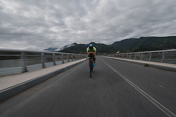 Image showing triathlon athlete riding a bike on morning training