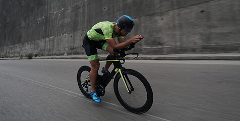 Image showing triathlon athlete riding a bike on morning training