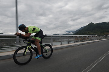 Image showing triathlon athlete riding a bike on morning training