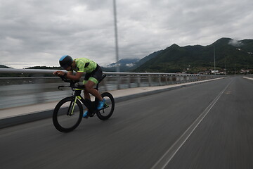 Image showing triathlon athlete riding a bike on morning training