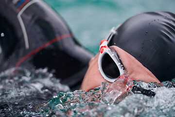 Image showing triathlon athlete swimming on lake wearing wetsuit