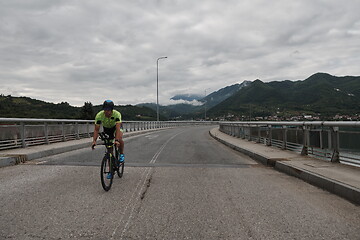 Image showing triathlon athlete riding a bike on morning training