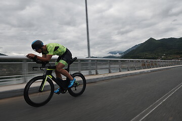 Image showing triathlon athlete riding a bike on morning training