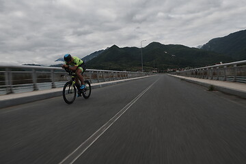 Image showing triathlon athlete riding a bike on morning training