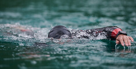 Image showing triathlon athlete swimming on lake wearing wetsuit