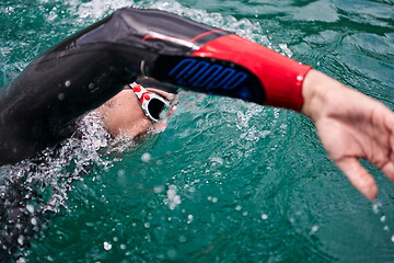 Image showing triathlon athlete swimming on lake wearing wetsuit