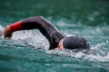 Image showing triathlon athlete swimming on lake wearing wetsuit