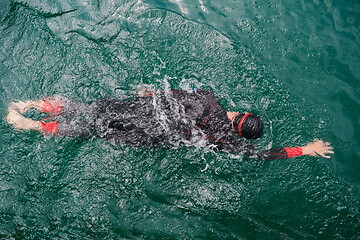 Image showing triathlon athlete swimming on lake wearing wetsuit