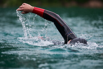 Image showing triathlon athlete swimming on lake wearing wetsuit