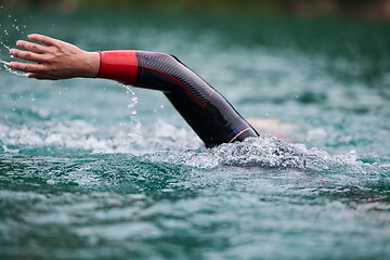 Image showing triathlon athlete swimming on lake wearing wetsuit