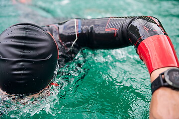 Image showing triathlon athlete swimming on lake wearing wetsuit