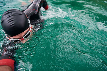 Image showing triathlon athlete swimming on lake wearing wetsuit