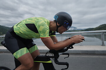 Image showing triathlon athlete riding a bike on morning training