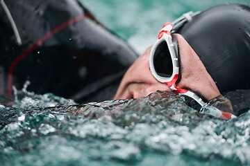 Image showing triathlon athlete swimming on lake wearing wetsuit