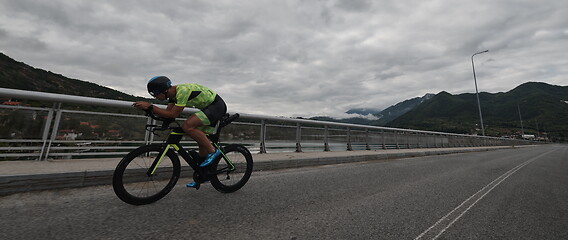 Image showing triathlon athlete riding a bike on morning training