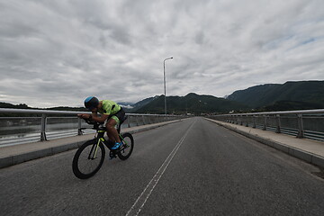 Image showing triathlon athlete riding a bike on morning training