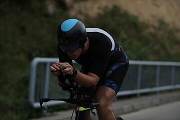 Image showing triathlon athlete riding a bike wearing black