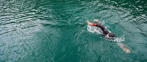 Image showing triathlon athlete swimming on lake wearing wetsuit