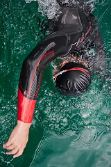 Image showing triathlon athlete swimming on lake wearing wetsuit