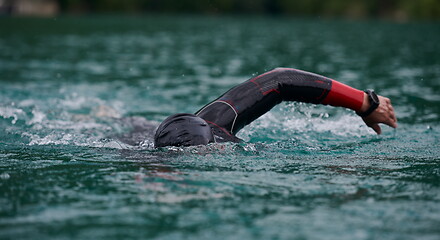 Image showing triathlon athlete swimming on lake wearing wetsuit
