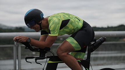 Image showing triathlon athlete riding a bike on morning training