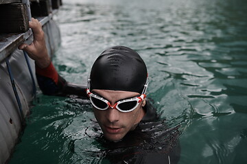 Image showing triathlon athlete swimming on lake wearing wetsuit