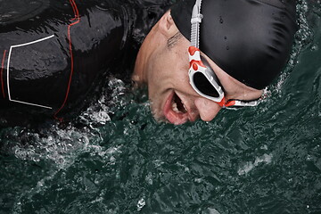 Image showing triathlon athlete swimming on lake wearing wetsuit