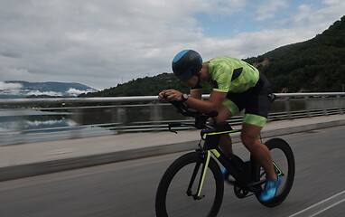 Image showing triathlon athlete riding a bike on morning training