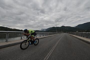 Image showing triathlon athlete riding a bike on morning training