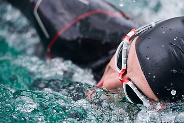 Image showing triathlon athlete swimming on lake wearing wetsuit