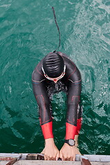 Image showing triathlon athlete swimming on lake wearing wetsuit