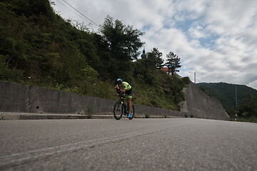 Image showing triathlon athlete riding a bike on morning training