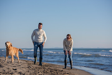 Image showing couple with dog having fun on beach on autmun day